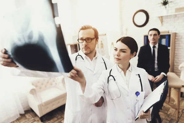 Läkare med stetoskop och sjuksköterska undersöker röntgenbild av affärsman, av patienten. — Stockfoto