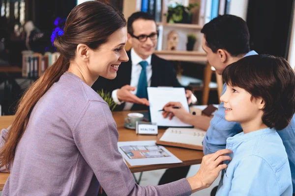 Makelaar zit aan de balie in kantoor. Vader is het ondertekenen van document voor nieuwe appartement. — Stockfoto