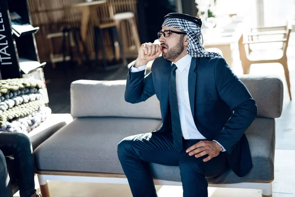 Arabisk affärsman hosta sitter på soffan på hotellrum. — Stockfoto