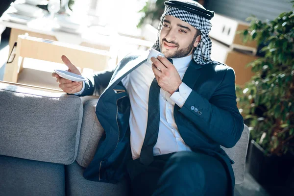 Arab businessman on couch with coffee at hotel room. — Stok fotoğraf