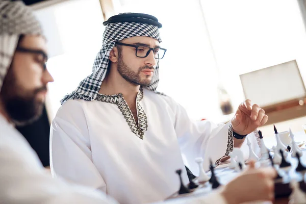 Två arabiska affärsmän som spelar schack vid bordet på hotellrummet. — Stockfoto