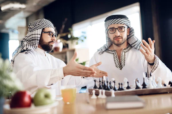 Två arabiska affärsmän argumentera spela schack vid bord på hotellrum. — Stockfoto