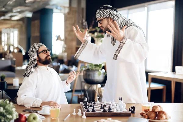 Två arabiska affärsmän argumentera spela schack vid bord på hotellrum. — Stockfoto