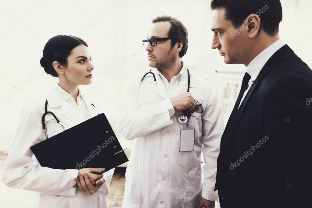 Doctor with stethoscope takes bribe from successful businessman, looking around. Bribe.