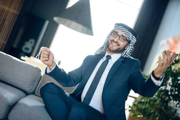 Arabische zakenman met parels op de Bank op de hotelkamer. — Stockfoto