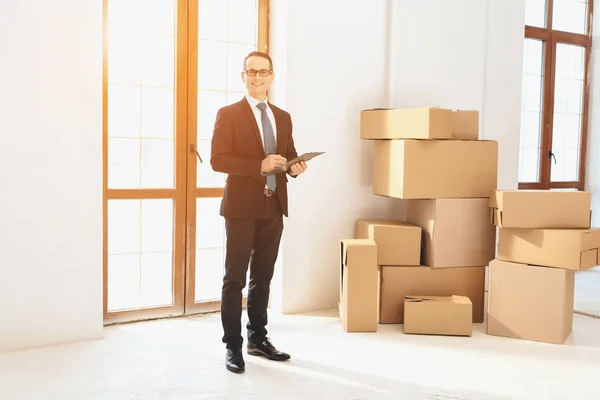 Realtor with clipboard in new apartment with cardboard boxes. — Φωτογραφία Αρχείου