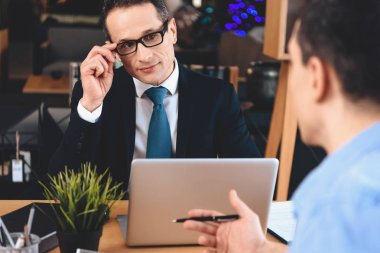 Emlak ofis masasında oturuyor. Baba ve oğul yeni apartment hakkında soruyorsun.