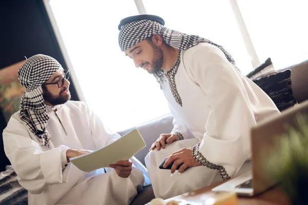 Twee Arabische zakenlieden met papieren op tafel op hotelkamer. — Stockfoto