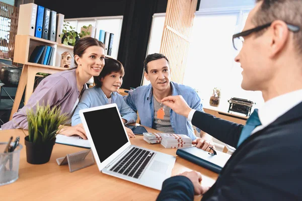 Realtor sitting at desk in office. Realtor is presenting keys for new apartment to family. — 图库照片