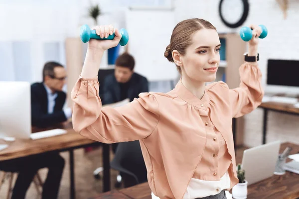 A girl is doing gymnastic exercises at work.