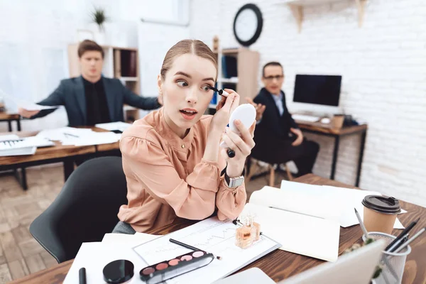 Een vrouw doet make-up op haar werkplek. — Stockfoto