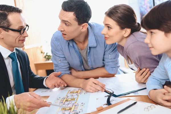 Makler sitzt am Schreibtisch im Büro. Makler diskutiert mit Vater, Mutter und Sohn über Wohnungsaufteilung. — Stockfoto