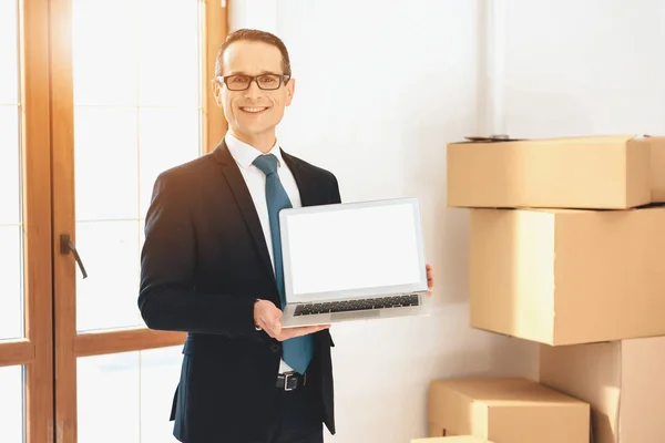 Realtor presenting laptop in new apartment with cardboard boxes. — Φωτογραφία Αρχείου