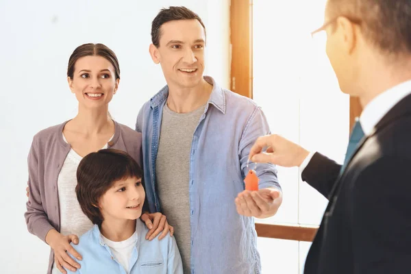 Makelaar presenteert sleutels naar familie in nieuw appartement met kartonnen dozen. — Stockfoto