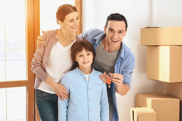 Πατέρα, μητέρα και γιος στο νέο διαμέρισμα με κουτιά από χαρτόνι. Ο πατέρας κρατώντας τα πλήκτρα. — Φωτογραφία Αρχείου