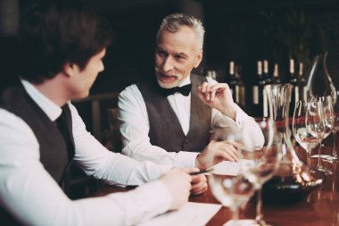Deneyimli sommelier şarap içecek restoranda oturan tat nitelikleri hakkında notlar yapar.