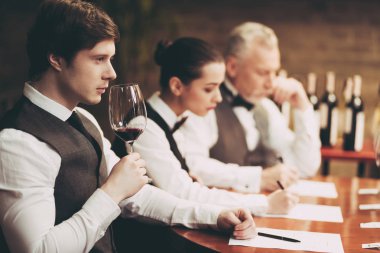 Experienced sommelier explores taste of wine in restaurant. Young waiter tastes alcoholic beverages.
