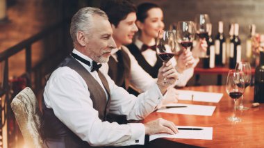 Üç sommeliers tat ve renk nitelikleri şarap cam restoranda incelerken değerlendirmek.