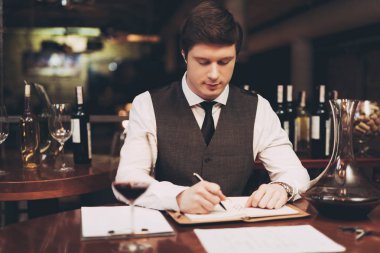Genç emin sommelier defter, restoranda şarap tatma notlar yapar. Şarap tadımı.