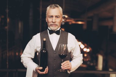 Papyon deneyimli sommelier şarap ve şarap cam şişesiyle duruyor.