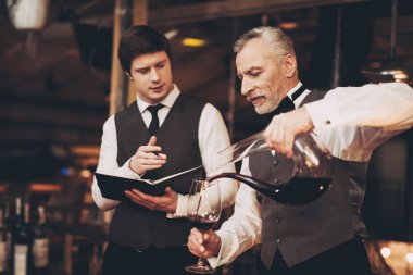 İki deneyimli sommeliers şarabın tadını. Sommelier sürahi kırmızı şarap cam içine dökülen..
