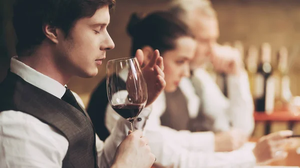 Professional sommelier tastes red wine in restaurant. Sommelier checks aging of wine. — Stock Photo, Image