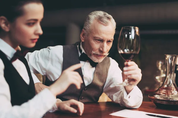 El experimentado sumiller seguro de sí mismo mira una copa de vino mientras está sentado en el restaurante. Degustación de vinos . — Foto de Stock