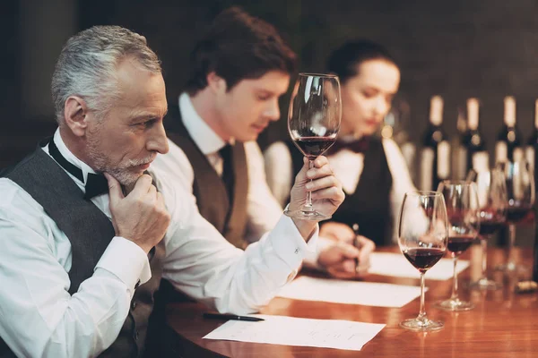 Viejo sommelier experimentado en corbata de lazo está degustando vino en copa. Degustación de vinos . — Foto de Stock