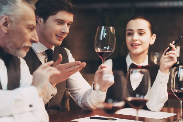 Üç sommeliers tat ve renk nitelikleri şarap cam restoranda incelerken değerlendirmek.