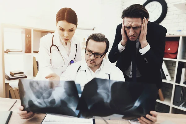 Взрослый бизнесмен в ужасе от диагноза врача, который ведет радиографию в медицинском кабинете . — стоковое фото