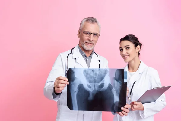 Portrait of male and female doctors with stethoscopes holding x-ray and clipboard isolated. — Stock Fotó