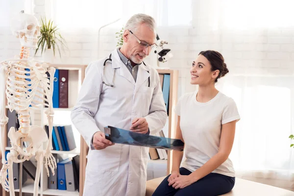 Läkare med stetoskop och kvinnlig patient i office. Läkare visar röntgen av höfter. — Stockfoto