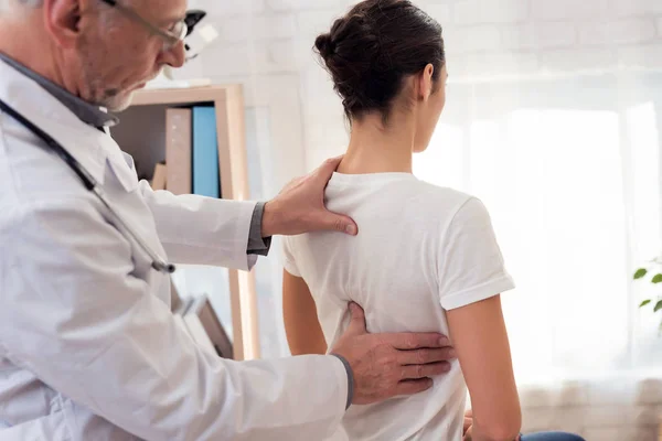 Dokter dengan stetoskop dan pasien wanita di kantor. Dokter sedang memeriksa punggung wanita. . — Stok Foto