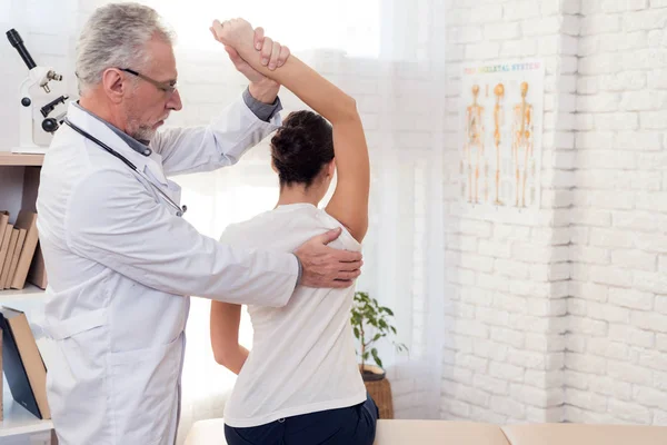 Läkare med stetoskop och kvinnlig patient i office. Läkaren undersöker kvinnans rygg. — Stockfoto