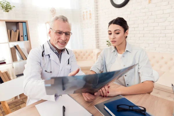 Doctor with stethoscope and female patient in office. Doctor is showing x-ray. — ストック写真