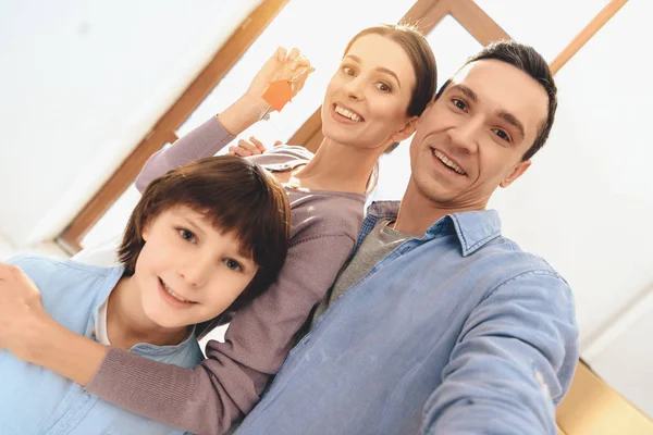 Vater, Mutter und Sohn in einer neuen Wohnung mit Kartons. Familie macht Selfie am Telefon. — Stockfoto