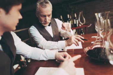 Deneyimli sommelier şarap içecek restoranda oturan tat nitelikleri hakkında notlar yapar.