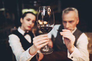 Sommelier şarap çökeller okuyor. Garsona kırmızı şarap tutar. Şarap tadımı.