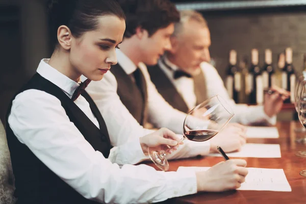 Sommelier femenino degustación de vino tinto y toma notas en la tarjeta de degustación . — Foto de Stock
