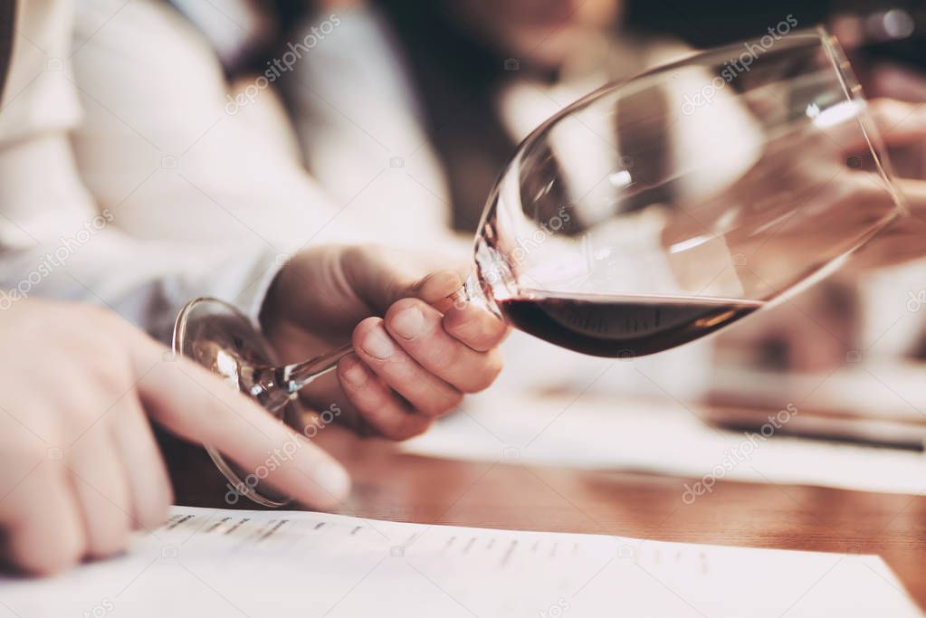 Close up. Tasting taste of wine. Man's hand holds glass of red wine. Wine tasting.