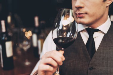 Yakın çekim. Emin yakışıklı sommelier şarap cam elinde tutan restoranında, tatma.