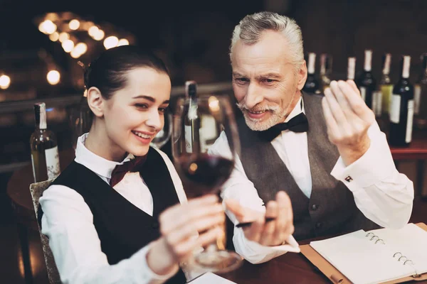 Viejo sommelier experimentado le dice a la joven sobre los detalles del sabor del vino tinto en el restaurante . — Foto de Stock