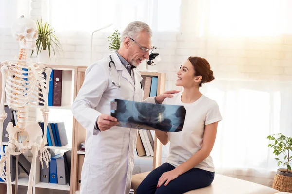 Läkare med stetoskop och kvinnlig patient i office. Läkare visar röntgen av höfter. — Stockfoto