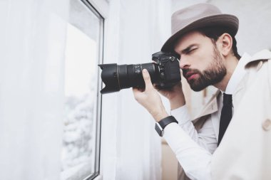 Özel dedektiflik bürosu. Adam pencerede fotoğraf alıyor.