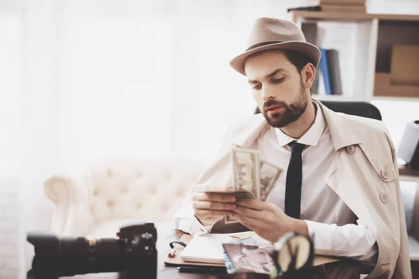 Privatdetektiv. Mann sitzt am Tisch und zählt Geld. — Stockfoto