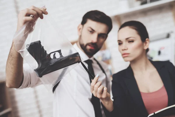 Agencia de detectives privados. El hombre y la mujer están mirando pistas de armas y tomando notas . — Foto de Stock