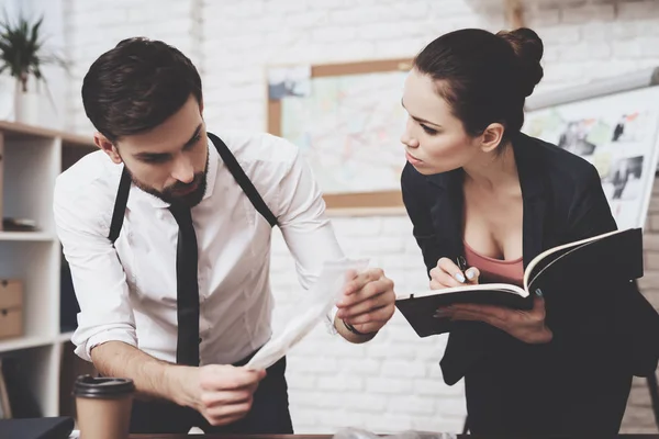 Agence de détectives privés. L'homme regarde l'indice, la femme prend des notes dans le carnet . — Photo