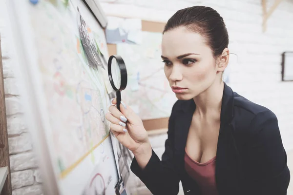 Prive-detective bureau. Vrouw is op zoek naar aanwijzing kaart met vergrootglas in kantoor. — Stockfoto