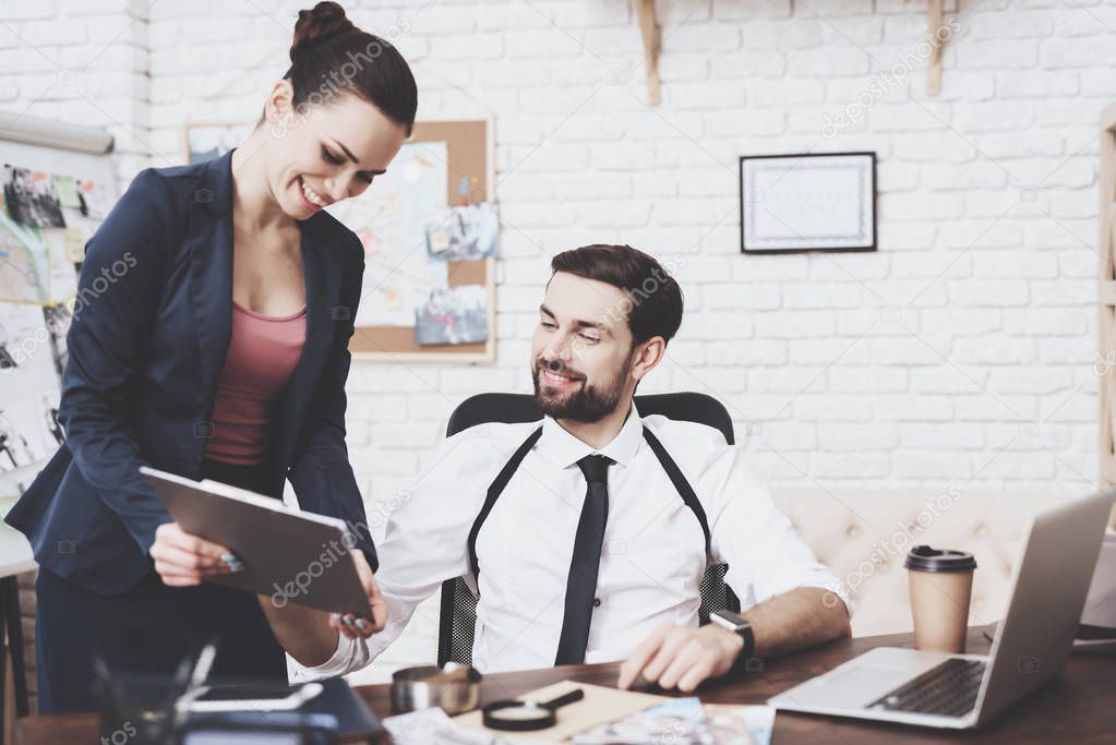 Private detective agency. Man and woman are looking at tablet in office.