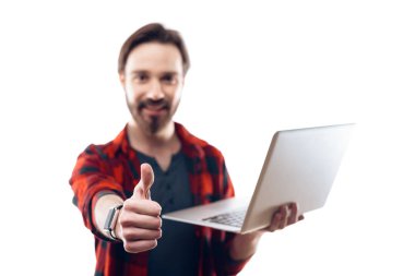 Adam tutarak Laptop ve yumuşak odak Yaşasın gösterir. Başparmak yukarıya el kamera odak. Beyaz arka plan üzerinde izole kırmızı kareli gömlekli bulanık yakışıklı sakallı adam. İnsanların duyguları kavramı